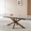 Marble-top dining table with a geometric wooden base, set with croissants and a coffee cup in a bright room.