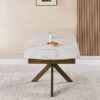 Modern marble-top dining table with wooden X-frame legs in a beige room, topped with a cup and saucer and a croissant on a small plate.